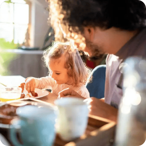 a toddler girl eating with her dad