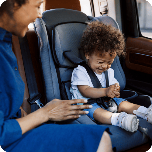 a little toddler smiling in their car seat next to mom