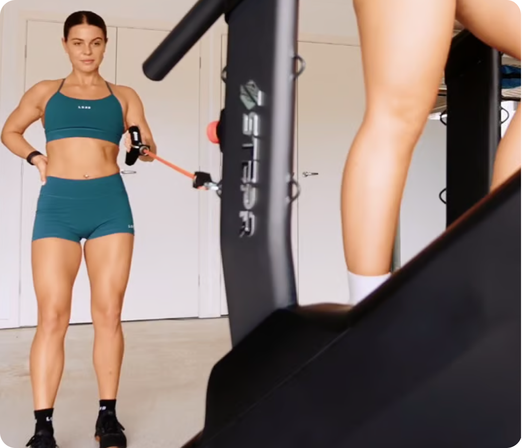 Woman using resistance bands beside a STEPR machine while another person climbs.