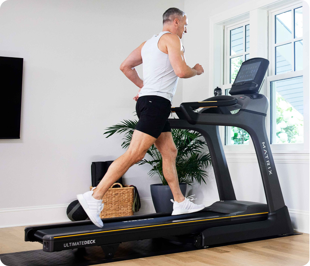 Man running on a Matrix treadmill in a bright home gym.