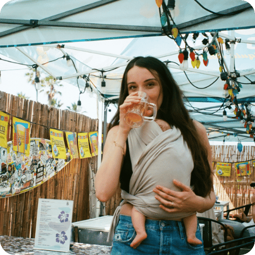 Writer fortesa latifi wearing her infant daughter and sipping a drink