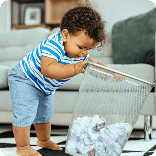 a toddler boy digging in the trash