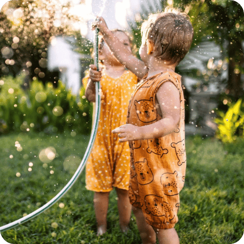 two toddlers playing with the hose