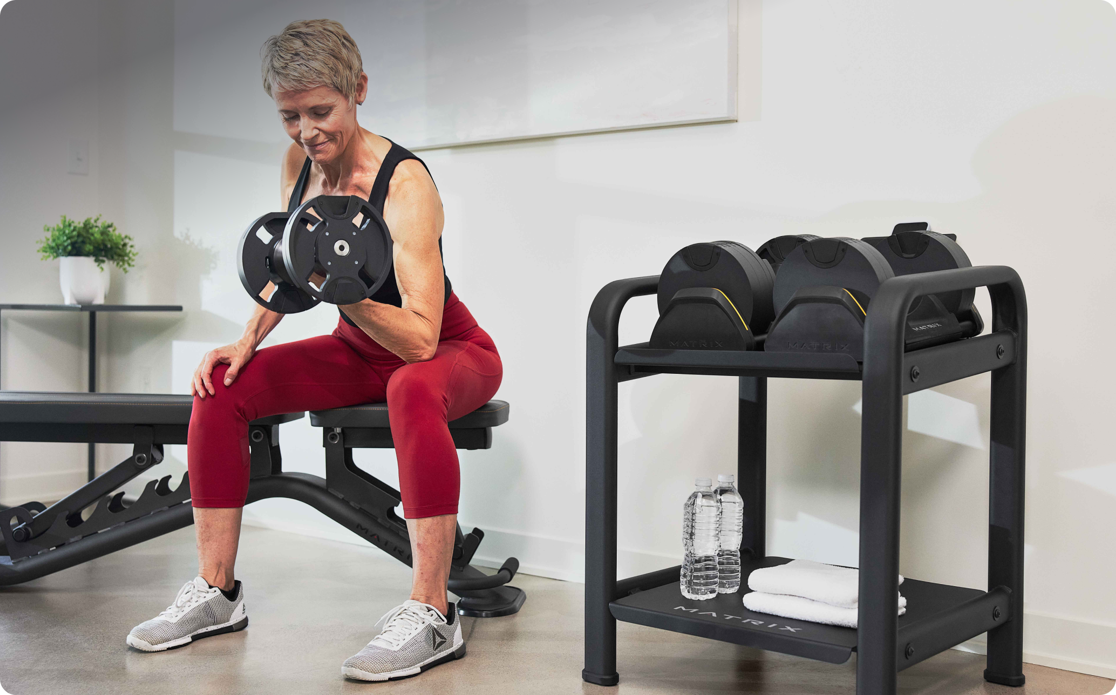 Woman using Matrix adjustable dumbbells at home. Woman using Matrix adjustable dumbbells at home.