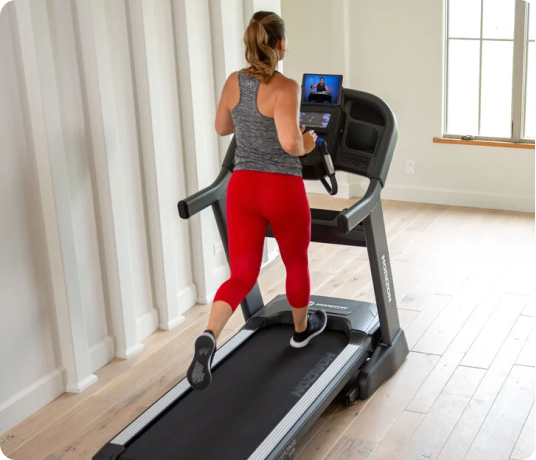 Woman running on a Horizon treadmill in a bright home gym.