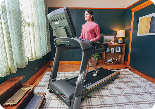 Woman walking on a Matrix treadmill in a home workout space.?lid=c3yakdmuxrmt