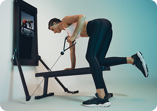 Woman performing a strength exercise with Tonal in a home workout space.