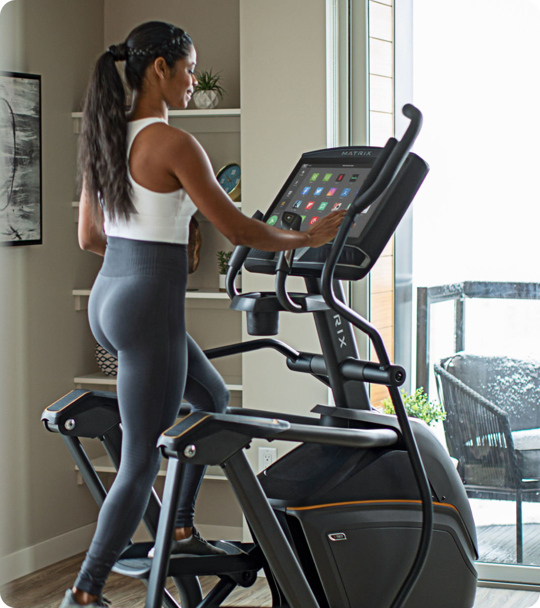 Woman exercising on a Matrix elliptical in a home workout space.