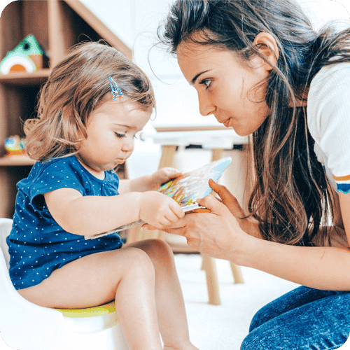 a mom sitting with her toddler who is on the potty
