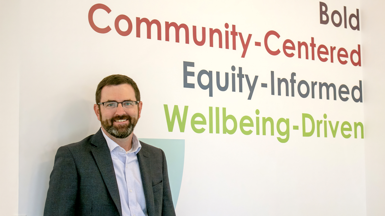 Photo of a man leaning against a wall with company values