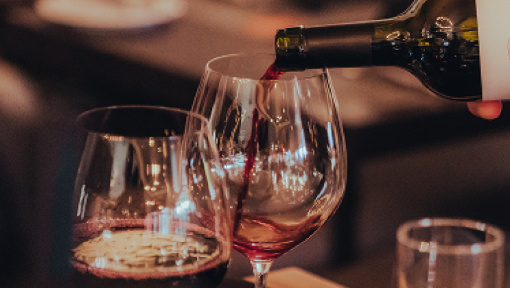 Red wine being poured into glasses during a tasting event