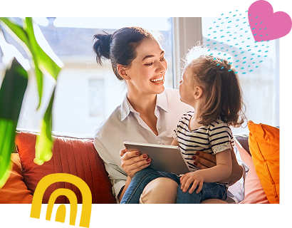 A mother and daughter laughing together on a couch while looking at a tablet