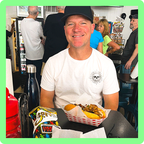 Image Description: A man with a hat sitting with a po’boy in front of him